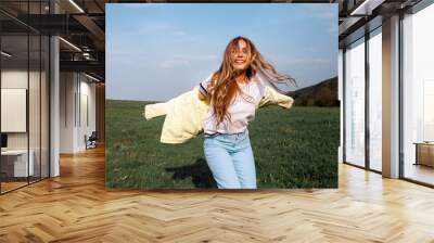 Outdoors lifestyle fashion portrait of happy smilling blonde girl. Beautiful smile. Long curly light hair. Wearing stylish yellow jacket and jeans. Joyful and cheerful woman. Happiness Wall mural