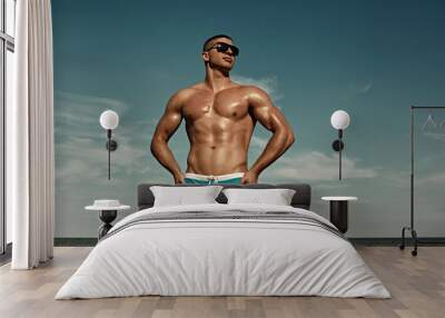 Summer vacation. Sexy muscular man on the beach in sunglasses.. Wall mural