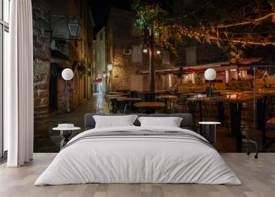 Empty street cafe terrace with tables and chairs in an old town of Budva at night, Montenegro. Wall mural