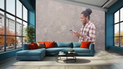 portrait of happy young bearded black man in casual dress using tablet or laptop, smartphone Wall mural