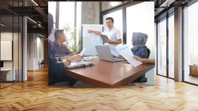 young professional male presentation at group meeting in white board with tablet and laptop, office  Wall mural