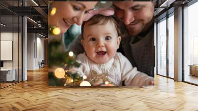 A family of three, a man, a woman and a baby, are gathered around a Christmas tree Wall mural