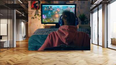 A man is playing a video game on a computer monitor. He is wearing headphones and a pink hoodie Wall mural