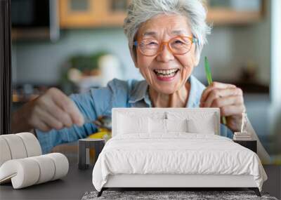 A woman is smiling and eating a bowl of food. She is wearing glasses and has a spoon in her hand Wall mural