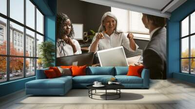 Multi ethnic team at business meeting in office. Focus on Asian white-headed mature businesswoman gesturing while presenting ideas to colleagues Wall mural