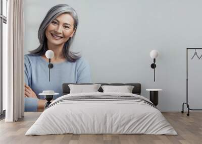 Smiling Asian senior woman with crossed arms Wall mural