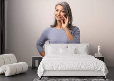 Smiling Asian woman touches her grey hair Wall mural