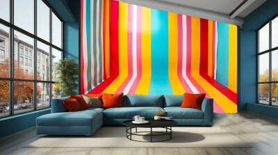 A vibrant room with red, yellow, blue, pink, green, orange, white, and black stripes forms a dynamic backdrop for product photography. Long shadows enhance depth, creating an artistic setting ideal fo Wall mural