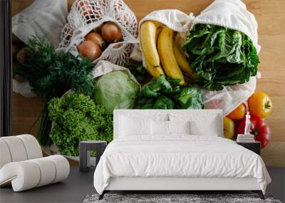 Fresh vegetables and fruits in eco cotton bags on table in the kitchen. Wall mural