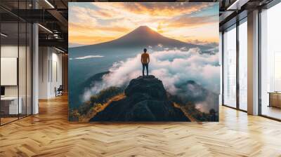 Strong and confident man standing on to a mountain. Fit active lifestyle concept. Positive man celebrating on mountain top, with arms raised up, Goal, successful, achievement. Strong and confident man Wall mural