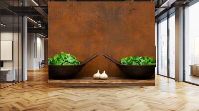 Two bowls of fresh green leafy vegetables with garlic on rustic wooden table against a textured brown background Wall mural