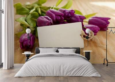 Purple tulips with white card on wood background. Wall mural