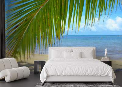 Tropical beach with palm tree branch and Caribbean sea. Wall mural