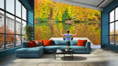 Woman meditating outdoors in the autumn park near forest lake. Wall mural