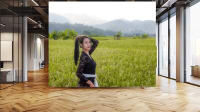 a beautiful Indonesian woman wearing a black Balinese kebaya with a background of rice fields and mountains Wall mural