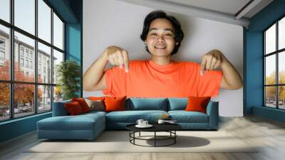 Portrait of an Asian Indonesian young man wearing a orange shirt with a random expression when photographed with an isolated white background Wall mural