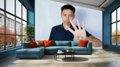 serious asian man giving four finger sign. white background Wall mural