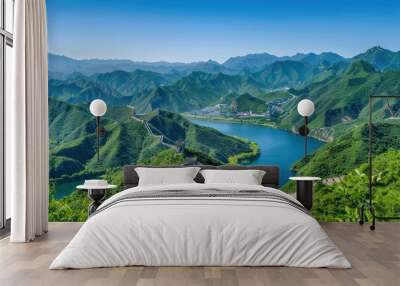 A picturesque scene of the Great Wall of China snaking through lush green mountains, under a clear blue sky Wall mural