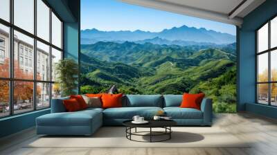 A picturesque scene of the Great Wall of China snaking through lush green mountains, under a clear blue sky Wall mural