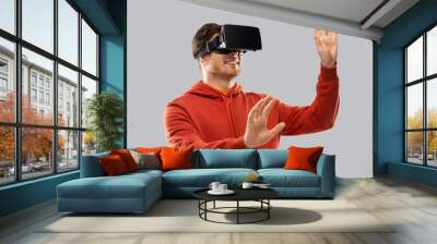 3d technology, virtual reality, entertainment and people concept - happy young man in vr glasses playing game and touching something imaginary over grey background Wall mural