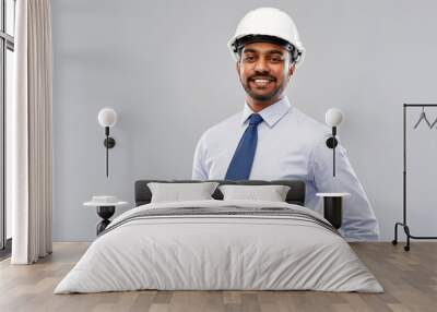 architecture, construction business and building - smiling indian architect or businessman in helmet with blueprints over grey background Wall mural