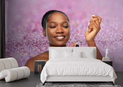 beauty, luxury and people concept - portrait of young african american woman with bare shoulders with make up blending sponge over purple glitter background Wall mural