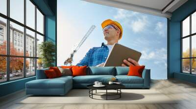 builder in hardhat with tablet pc at construction Wall mural