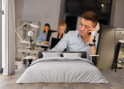 business, deadline and technology concept - man with computer calling on smartphone and taking notes late at night office Wall mural