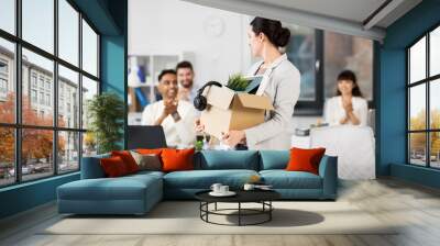 business, job and quit concept - female office worker with box of personal stuff and happy smiling colleagues applauding Wall mural