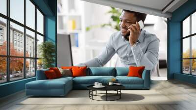 business, people, communication and technology concept - smiling african american businessman with computer calling on smartphone at office Wall mural