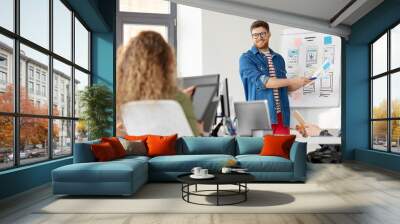 business, technology and people concept - man showing user interface design on flip chart to creative team at office presentation Wall mural