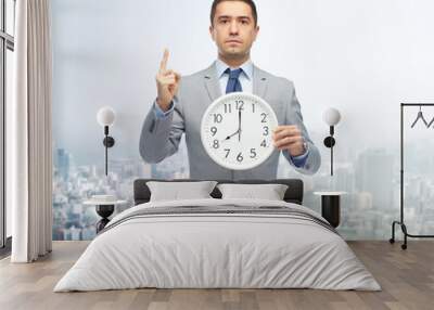 businessman in suit holding clock with 8 o'clock Wall mural