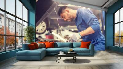 car service, repair, maintenance and people concept - auto mechanic man with lamp working at workshop Wall mural