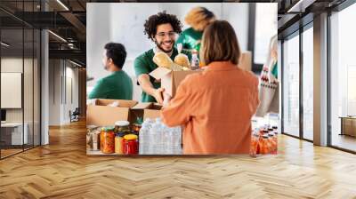 charity, donation and volunteering concept - happy smiling male volunteer giving box of food to woman at distribution center at distribution or refugee assistance center Wall mural