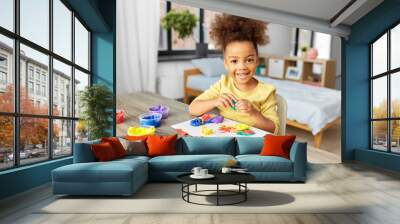 childhood, creativity and hobby concept - little african american girl with modeling clay playing at home Wall mural