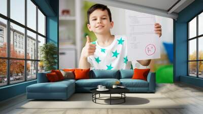 childhood, education and people concept - happy smiling boy holding school test with a grade showing thumbs up Wall mural