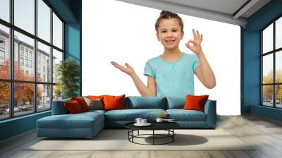 childhood, fashion and people concept - happy smiling girl holding something imaginary over white background Wall mural