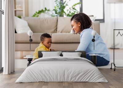 childhood, kids and people concept - happy african american mother and her baby son playing together with wooden toy blocks kit on floor at home Wall mural