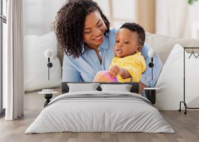 childhood, kids and people concept - happy african american mother and her baby son playing with ball together on sofa at home Wall mural