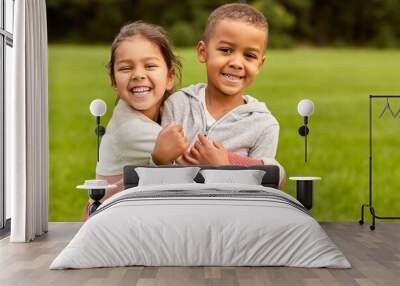 childhood, leisure and people concept - happy smiling little boy and girl hugging at park Wall mural