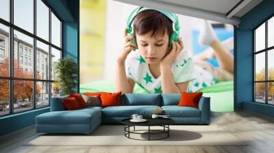 childhood, technology and people concept - boy with tablet pc computer and headphones lying on bed at home Wall mural