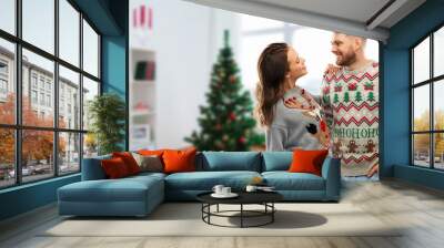 christmas, people and holidays concept - portrait of happy couple at ugly sweater party over home room background Wall mural