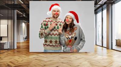 christmas, photo booth and holidays concept - happy couple in ugly sweaters posing with party props Wall mural