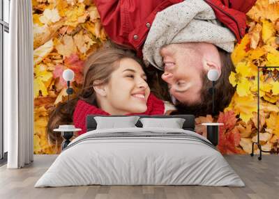 close up of smiling couple lying on autumn leaves Wall mural