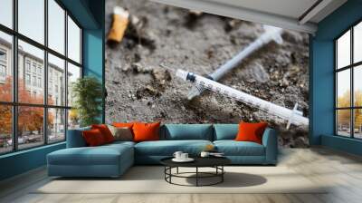 close up of syringe and smoked cigarette on ground Wall mural