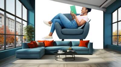 comfort, people and furniture concept - happy smiling young african american woman sitting in modern armchair and reading book over white background Wall mural