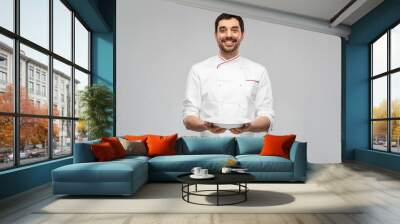 cooking, culinary and people concept - happy smiling male chef holding empty plate over grey background Wall mural