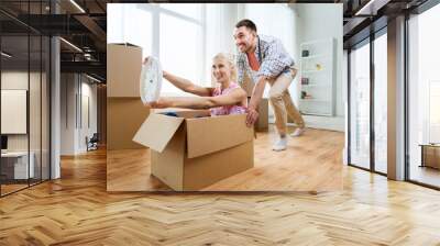 couple with cardboard boxes having fun at new home Wall mural