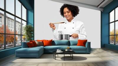 culinary and people concept - happy smiling female chef in jacket with saucepan cooking food over grey background Wall mural