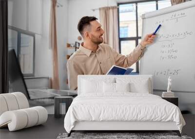 distant education, school and remote job concept - happy smiling male math teacher with laptop compute and book showing equation on flip chart having online class or video call at home office Wall mural